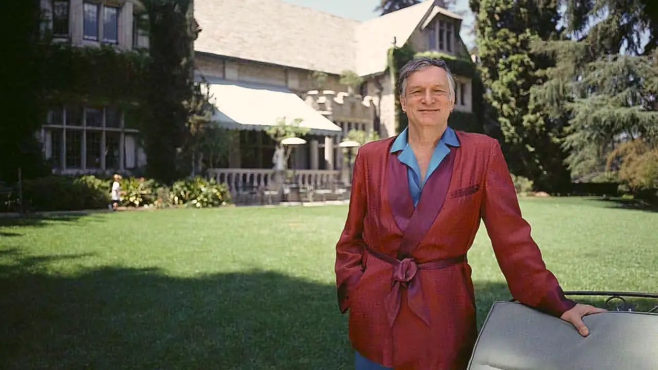 Hugh Hefner posing in front of Playboy Mansion